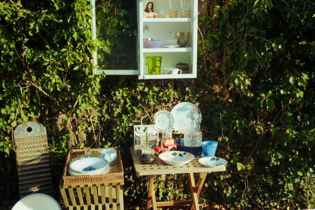 Charming outdoor table with vintage dishes set against lush greenery.